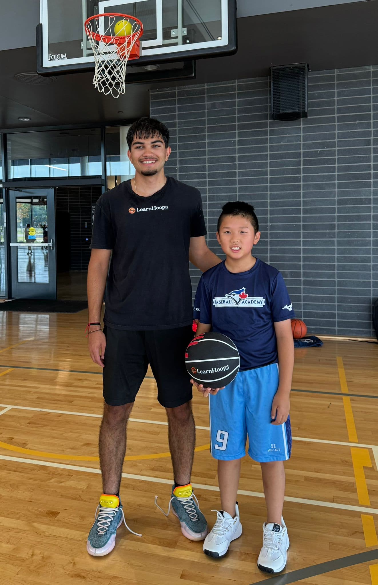 A LearnHoops coach on the court with a young player holding a LearnHoops training basketball
